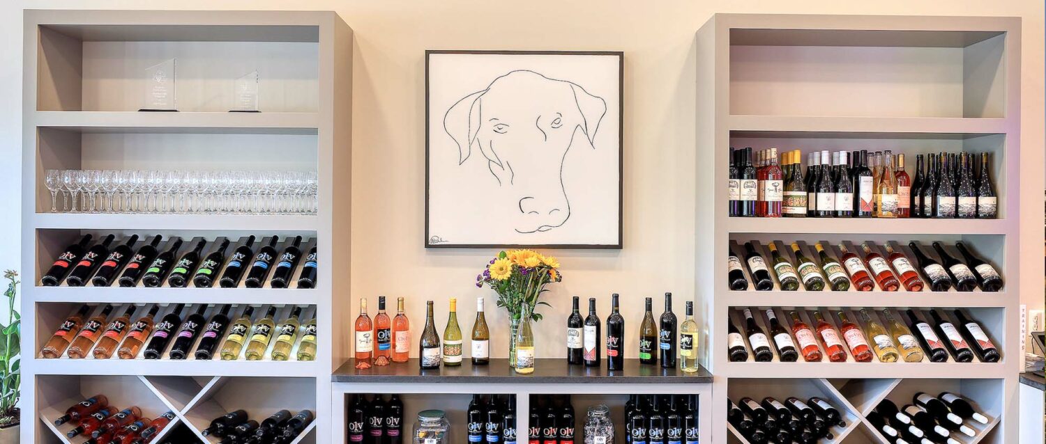 October One Vineyard Leesburg Wine Tasting Shop Interior Photo with Dog Artwork and Wine Bottles Displayed behind the counter